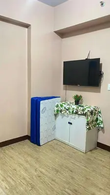 a room with a table and a tv on a wall at transient room anuva condominium in Manila