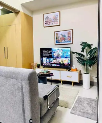 a living room with a couch and a flat screen tv at Taguig Parksuit 1BGC in Manila