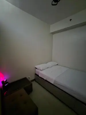 a room with a bed and a table with a pink light at DreamEscape by Charm Residences in Manila