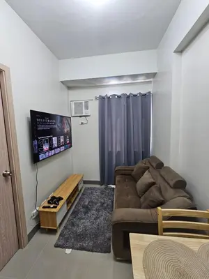 a living room with a couch and a flat screen tv at DreamEscape by Charm Residences in Manila