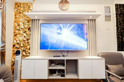 a large television in a living room with a clock at Sapphira Manor Luxurious Condo by the Bay in Manila