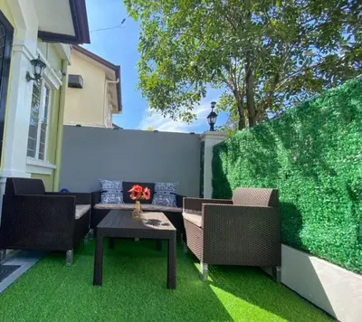 a patio with two chairs and a table on green grass at Modern Home Near MOA and NAIA in General Trias