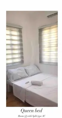 a bedroom with a bed with white sheets and two windows at Modern Home Near MOA and NAIA in General Trias