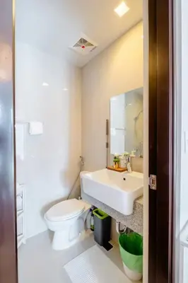a white bathroom with a toilet and a sink at Uptown BGC in Manila