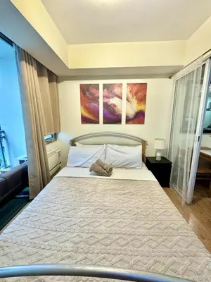 a bedroom with a bed with two paintings on the wall at Aesthetic Beach View Unit in Azure Parañaque in Manila