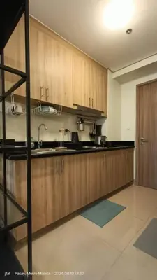 a kitchen with wooden cabinets and a sink at Modern Rustic 1-Bed Condo in MoA Complex in Manila