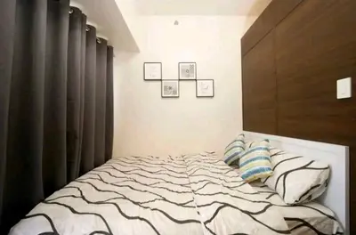 a bedroom with a bed with a wooden headboard at 1br at Air Makati Ayala near Makati med in Manila