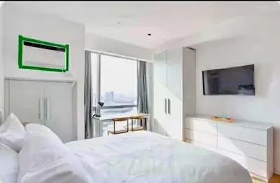 a white bedroom with a large bed and a television at Deluxe Studio good for 3 adults in Novotel Suites Manila with City View in Manila