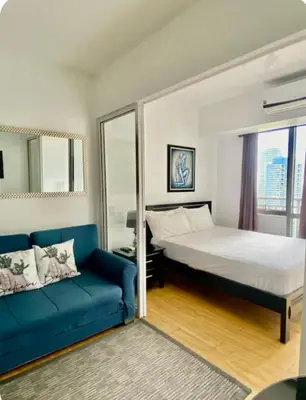 a bedroom with a bed and a blue couch at Deluxe Studio good for 3 adults in Novotel Suites Manila with City View in Manila