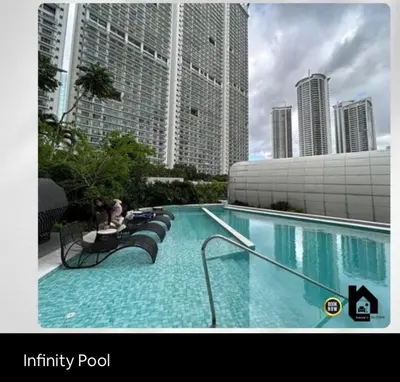 a large swimming pool in a city with tall buildings at Deluxe Studio good for 3 adults in Novotel Suites Manila with City View in Manila
