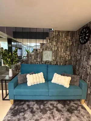 a blue couch in a living room with a clock at Modern Chic 2BR with Panoramic Golf View in BGC in Manila