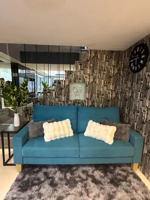 a blue couch in a living room with a clock at Modern Chic 2BR with Panoramic Golf View in BGC in Manila