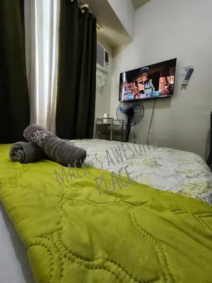 a bed with a green blanket and a tv on the wall at Macks Awesome 12 Place Fast Wifi Netflix in Manila