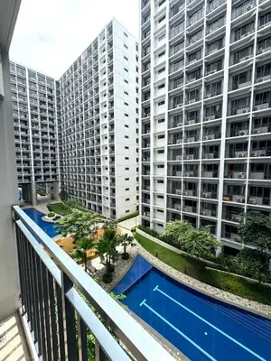 an apartment balcony with a swimming pool and two tall buildings at Katkat Shore 2 Staycation in Manila