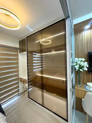 a glass cabinet in a room with a vase of flowers at Katkat Shore 2 Staycation in Manila