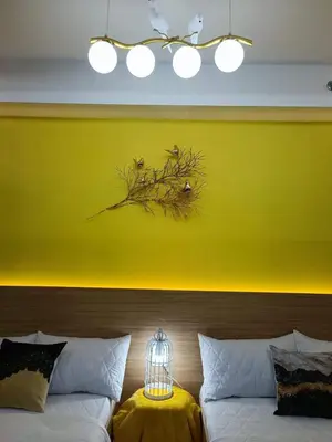 a yellow wall with a bird in a cage on a couch at Shore 2 Residences MOA DMBV in Manila