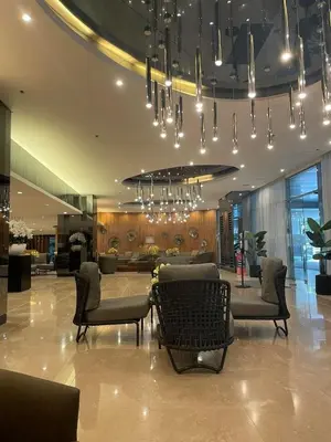 a lobby with chairs and a table and chandelier at Shore 2 Residences MOA DMBV in Manila