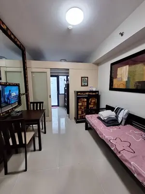 a bedroom with a bed and a table and a television at MOA Sea Residence - Oasis MNL in Manila