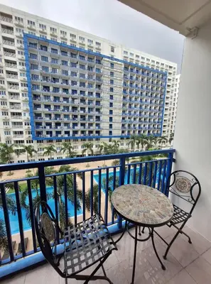 a balcony with a table and chairs and a large building at MOA Sea Residence - Oasis MNL in Manila