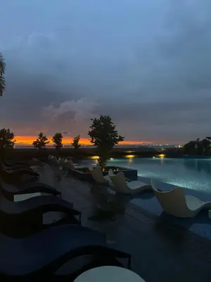a group of chairs sitting next to a pool at sunset at Stylish 1BR Near Airport Facing the Bay - 9d in Manila