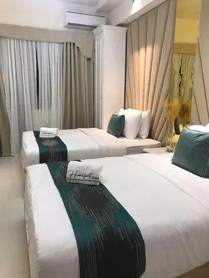 two beds in a hotel room with white and green at Homefort at Lush Residences Makati in Manila
