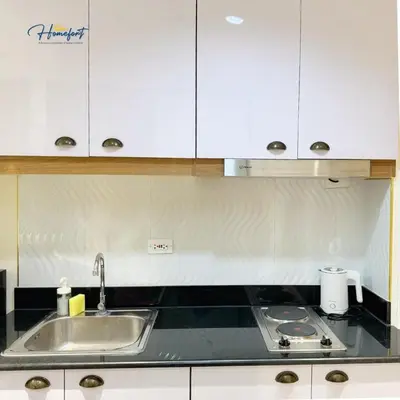 a kitchen with a sink and white cabinets at Homefort at Lush Residences Makati in Manila