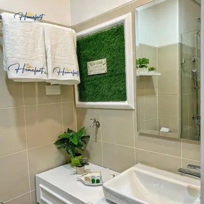 a bathroom with a sink and a mirror and a towel at Homefort at Lush Residences Makati in Manila
