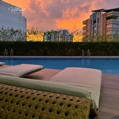 two beds sitting next to a pool with a sunset at Homefort at Lush Residences Makati in Manila