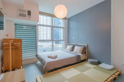 a bedroom with a bed and a large window at Japanese Stylish Condo in Makati in Manila