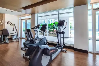 a gym with treadmills and ellipticals in front of a window at Japanese Stylish Condo in Makati in Manila