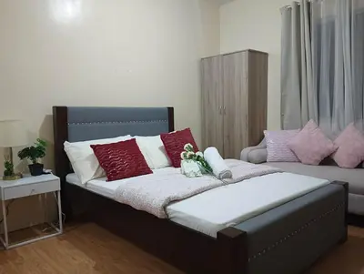 a bedroom with a bed with red and white pillows at Paradise Room in Las Piñas City in Manila