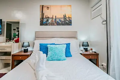 a bedroom with a white bed with blue pillows at Paradise Room in Las Piñas City in Manila
