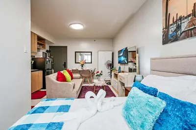 a bedroom with a bed and a living room at Paradise Room in Las Piñas City in Manila