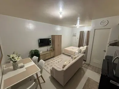 a living room with a couch and a bed and a television at Paradise Room in Las Piñas City in Manila