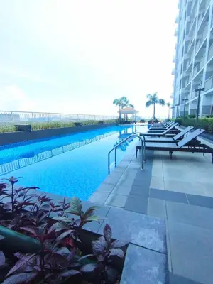 a large swimming pool with benches and a building at Coast Residences by Casa Stellar in Manila