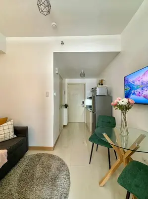 a living room with a glass table and green chairs at Cozy and Homey 1BR Condo at SMDC South Residences in Manila