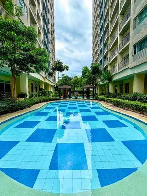 a large blue tile swimming pool in a building at Cozy and Homey 1BR Condo at SMDC South Residences in Manila