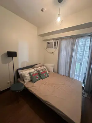 a bedroom with a bed with pillows and a window at Prisma Residences Astra Building in Manila