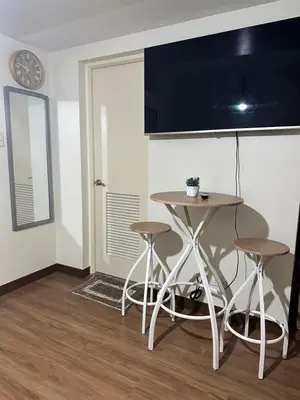a kitchen with a table and stools in a room at Prisma Residences Astra Building in Manila