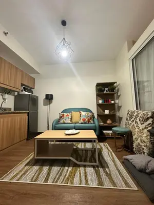 a living room with a blue couch and a coffee table at Prisma Residences Astra Building in Manila
