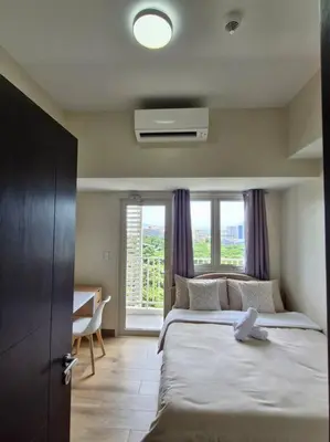 a bedroom with a large bed with a window at Modern & New, Work Desk, Fast Internet, Balcony in Manila