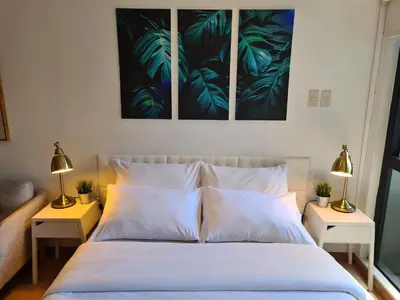 a bedroom with a bed with two lamps on two tables at Scandi Inspired Studio in Knightsbridge, Makati in Manila