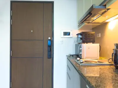 a kitchen with a counter top with a microwave at 1BR BGC, One Uptown Residence B001 in Manila