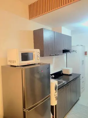 a kitchen with a microwave on top of a refrigerator at Bigg Apol Suite in Manila