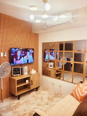 a living room with a flat screen tv on a wall at Bigg Apol Suite in Manila