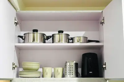 a cupboard with two pots and pans and plates at NEW! Studio Condo in Prisma Residences Pasig in Manila
