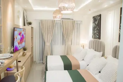 a white bedroom with two beds and a desk at Becca Suite by Crib2GO with Pool View in Manila