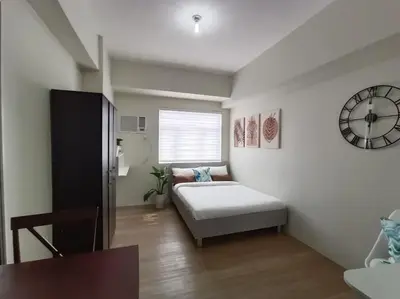 a bedroom with a bed and a clock on the wall at Vista GL Taft Studio Unit in Manila