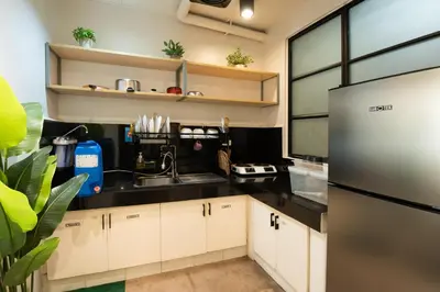 a kitchen with white cabinets and a stainless steel refrigerator at Homey and Cozey Poblacion Makati S01 in Manila