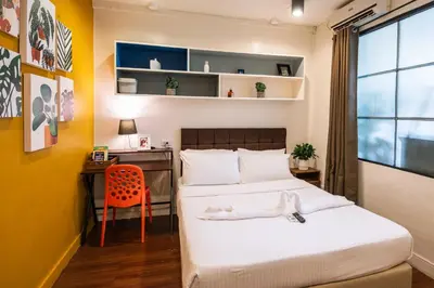 a bedroom with two beds and a desk and a chair at Homey and Cozey Poblacion Makati S01 in Manila